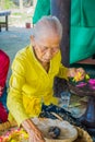 BALI, INDONESIA - MARCH 08, 2017: Old woman preparing an Indian Sadhu dough for chapati on Manmandir ghat on the banks