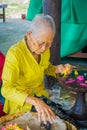 BALI, INDONESIA - MARCH 08, 2017: Old woman preparing an Indian Sadhu dough for chapati on Manmandir ghat on the banks