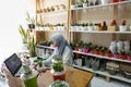 BALI/INDONESIA-MAY 25 2019: A Muslim businesswoman is selling succulent plants on internet. She has a clean and white workshop.