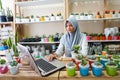 BALI/INDONESIA-MAY 25 2019: A Muslim businesswoman is selling succulent plants on internet. She has a clean and white workshop.