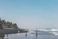 BALI, INDONESIA - MAY 19, 2018: Two fathers and 2 sons on the black sand beach.