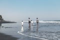 BALI, INDONESIA - MAY 19, 2018: Two fathers and 2 sons on the black sand beach.