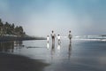 BALI, INDONESIA - MAY 19, 2018: Two fathers and 2 sons on the black sand beach.