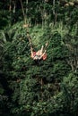 BALI, INDONESIA - MAY 16, 2018: Young woman swings in the jungle of Bali island. Rainforest of Indonesia. Travel concept