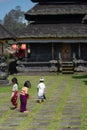 26.12.2018, Bali, Indonesia. Small Balinese children walk to the temple on a mossy path. Rear view Royalty Free Stock Photo