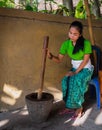 Bali - Indonesia 10.21.2015 - Young Balinese girl wearing traditional clothes grinding coffee beans by hand in an old mortar