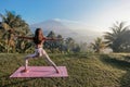 Woman with dark hair in sportive suit making yoga on sunrise with volcano Agung view