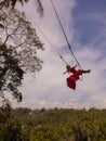 Bali swing trend. Caucasian woman in long red dress swinging in the jungle rainforest. Vacation in Asia. Travel lifestyle. Blue Royalty Free Stock Photo