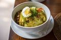 Balinese breakfast served in a white plate and bowl with egg, chicken