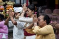 A Balinese family is praying with flowers on their fingers at a temple in Ubud, Bali.