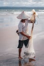 Balinese fisherman with a net and fish catch on the ocean.