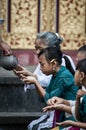 A Balinese girl receives holy water from a priest while praying at a temple in Ubud, Bali