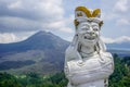Balinese statue with a drum on the background of the Batur volcano