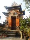 Balinese traditional building in the form of an entrance made of stone with a background of blue sky and green Royalty Free Stock Photo
