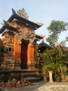 Balinese traditional building in the form of an entrance made of stone with a background of blue sky and green Royalty Free Stock Photo