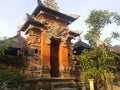 Balinese traditional building in the form of an entrance made of stone with a background of blue sky and green Royalty Free Stock Photo