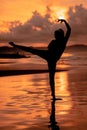 A Balinese woman in the form of a silhouette performs ballet movements very deftly and flexibly on the beach with the waves