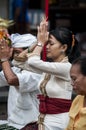 A Balinese woman praying with the flower in her finger.