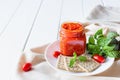 Balkan traditional dish ajvar, lutenitza, pingjur, with bread on a plate on white wooden table. Serbian traditional food