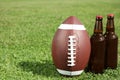 Ball for American football and beverage on fresh green field grass. Royalty Free Stock Photo