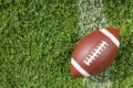 Ball for American football on fresh green field grass, top view. Royalty Free Stock Photo