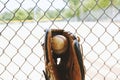 Ball in baseball glove by fence Royalty Free Stock Photo