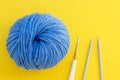 Ball of blue wool yarn, crochet hook and needles on bright yellow background. Knitting, handmade and hobby concept. Flat lay Royalty Free Stock Photo