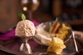 A ball of caramel ice cream with a mint leaf in an ice-cream bowl with carambola fruit on the background of a plate with sliced ch