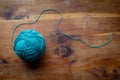 Ball of colorful aqua spun wool yarn with trailing string on a vintage wood table top, creative copy space