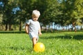 Concentrated small boy kicking a ball in the garden