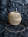 A ball of cord made of natural hemp laid on crumpled black wrapping paper Royalty Free Stock Photo