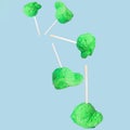 A ball of green ice cream on a stick falls and flies through the air until it lands on a flat surface. Pastel blue background Royalty Free Stock Photo