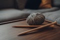 Ball of grey chunky wool yarn and a pair of crossed large wooden knitting needles on a table Royalty Free Stock Photo