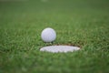 The ball at the hole on the golf course. Golf ball putting on green grass near hole golf to win in game at golf course with blur Royalty Free Stock Photo