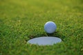 The ball at the hole on the golf course. Golf ball putting on green grass near hole golf to win in game at golf course with blur Royalty Free Stock Photo