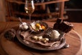 A ball of ice cream in a vintage metal ice-cream bowl on a wooden background with an assortment of cheeses in the background