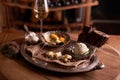 A ball of ice cream in a vintage metal ice-cream bowl on a wooden background with an assortment of cheeses in the background