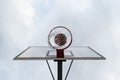 Ball inside red basketball hoop, basket against white sky. Outdoor basketball court. White board. Royalty Free Stock Photo