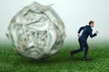 A ball made of dollars is rolling on a businessman. Financial crisis concept, debts, paying bills, mortgage, bankruptcy Royalty Free Stock Photo