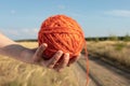 Ball of orange yarn in a female hand on the background of the road. Ariadne`s thread concept