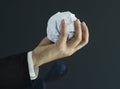 Ball of paper in hand on dark background, business concept