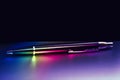 Ball pen illuminated with color rainbow light on matt surface, Royalty Free Stock Photo