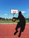 The ball in the player`s hands flies into the basketball ring on a sunny and clear day. Contour image of a basketball player. Mult