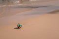 Ball at sandy beach close to seashore line. Blue yellow white stripes