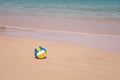 Ball at sandy beach close to seashore line. Blue yellow white stripes. Close up photo