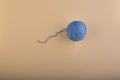 A ball of thread for knitting, soft blue, is slightly unwound on a harmonious light yellow textural background. Royalty Free Stock Photo