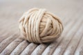 A ball of thread white acrylic yarn for knitting on a gray bedspread, cozy home interior