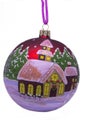 A ball on the tree with a snowy house and Christmas trees