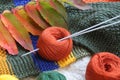 A ball of yarn with knitting needles on the background of knitted products with autumn foliage , close - up, side view-the concept