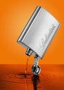 Ballantines Stainless hip flask with pouring out whiskey on an orange background